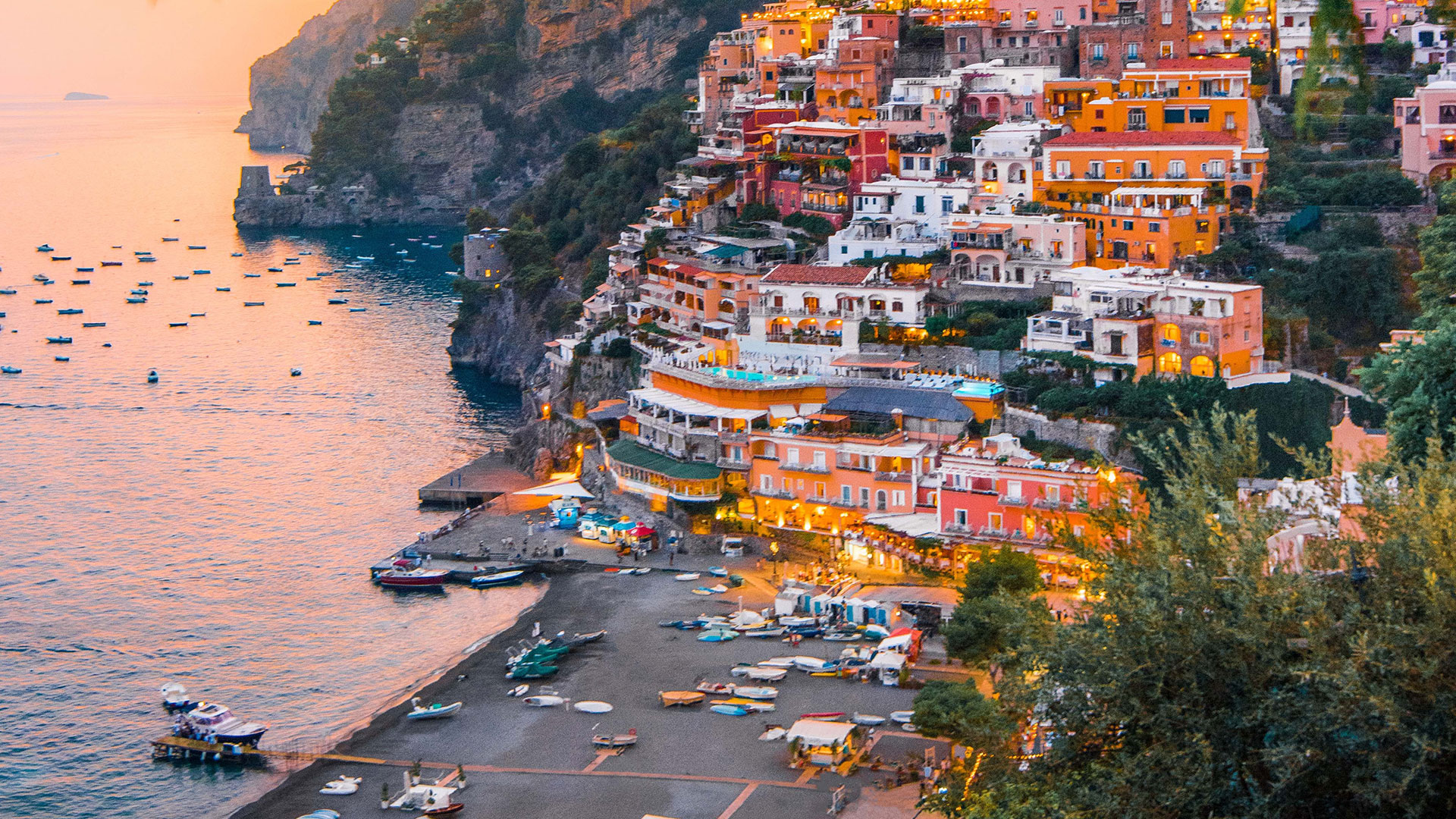Positano’s hillside houses above its beach at dusk