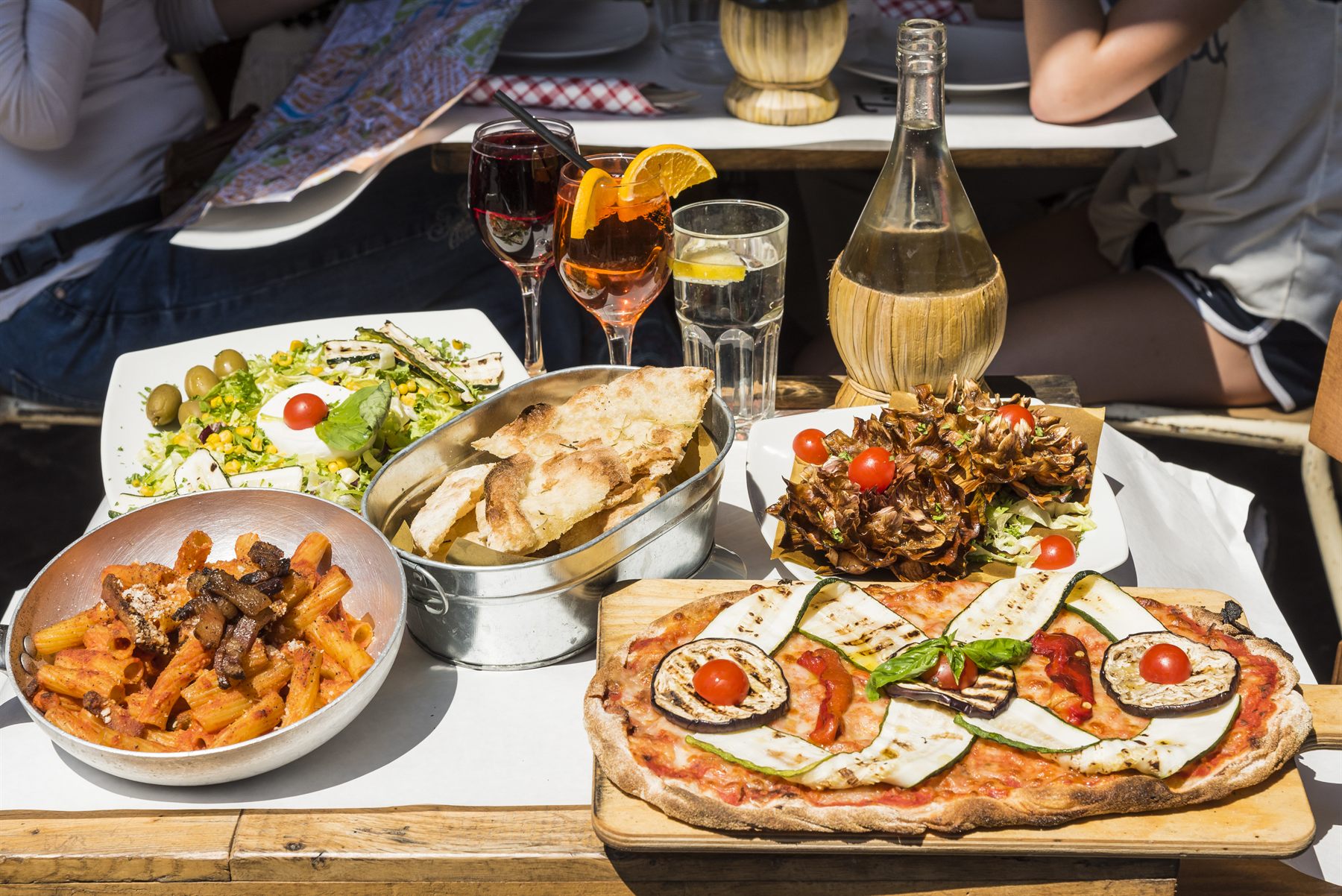 Pizza, pasta, salad and wine on a restaurant table