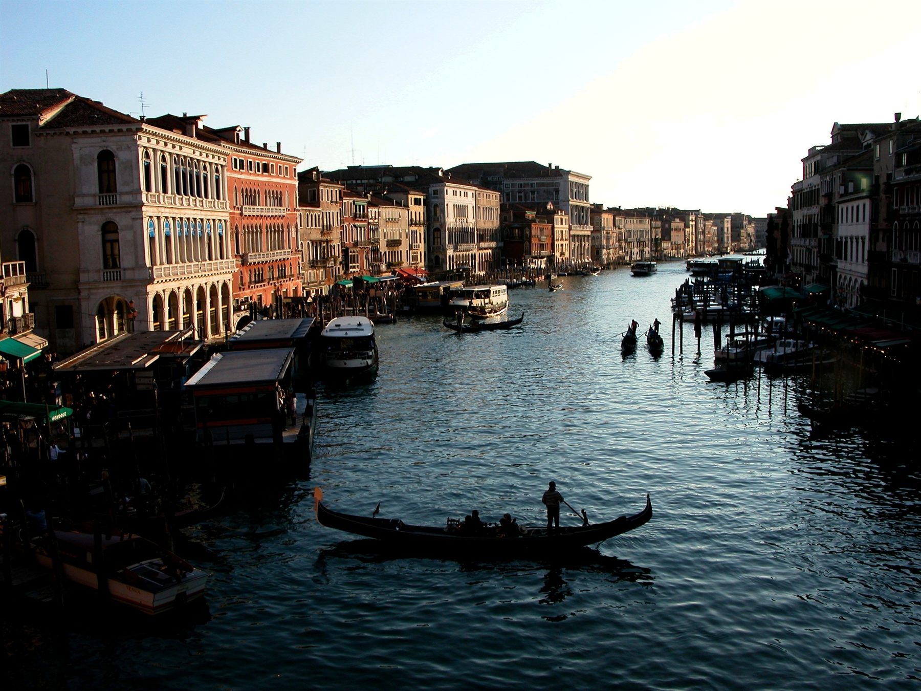 Gondola crossing a Venetian canal lined with palazzi and moored boats